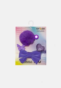 Violet Jibbitz žavesių rinkinys: su pūkuota pom-pom, drugeliu, širdimi ir dideliu kaspinu, visi ryškios violetinės spalvos medžiagose ir tekstūrose.