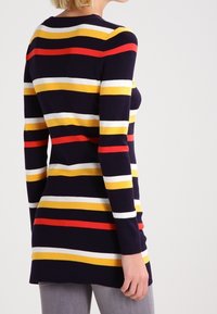 Pull à manches longues avec des rayures horizontales bleu marine, rouge, jaune et blanc, confectionné en maille avec un col rond et une coupe ajustée.