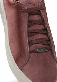 Sneaker in camoscio bordeaux con punta rotonda, lacci in stoffa e suola in gomma. Presenta una placca con logo in metallo e un design senza cuciture per una finitura liscia.
