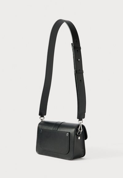 Melna ādas plecu soma ar taisnstūrveida formu, magnētisku aizdares klapīti un regulējamu siksnu. Aprīkota ar sudraba krāsas metāla detaļām un priekšējo kabatu.