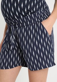 Marineblauwe shorts met een diamantpatroon in wit en lichtblauw. Gemaakt van zachte stof met een elastische tailleband en zijzakken.