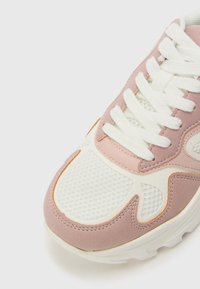 Sneaker con upper in suede rosa e mesh bianco, con suola in gomma testurizzata e lacci bianchi, progettato per traspirabilità e comfort.