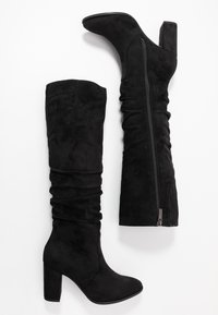 Black knee-high boots made of soft suede, featuring a slouchy design, high block heel, and side zipper. Smooth texture and solid color.