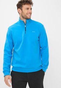 Pullover in fleece blu con zip a quarto, texture liscia e un logo discreto. Presenta un collo alto e maniche lunghe, progettato per il comfort.