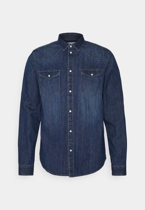 Camisa de mezclilla azul oscura de manga larga con cierre delantero de botones a presión, dos bolsillos con solapa en el pecho con botones a presión y cuello puntiagudo.