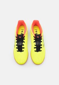 Bright yellow soccer shoes with black laces and accents. Features a textured upper and a contrasting red interior lining.