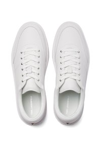 Fehér bőr tornacipők sima felülettel, kerek orral, lapos fűzős kivitelekkel és logóval a talpbetéten. Diszkrét részletek és ezüstszínű fűzőlyukak.