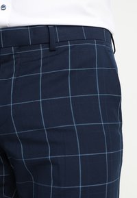 Marineblau karierte Hose mit einem subtilen Karomuster, aus glattem Stoff gefertigt, mit klassischem Schnitt und seitlichen Taschen.