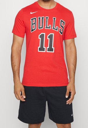 T-shirt rossa in cotone con la scritta "BULLS" e il numero "11" stampati in nero. Maniche corte, scollatura rotonda, abbinata a pantaloni corti neri con un logo.