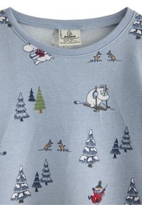 Vaaleansininen puuvillapaita, jossa on Muumi-hahmoja. Kuvastaa hiihtäjiä, puita ja leikkisiä eläimiä toistuvassa kuviokkeessa. Pyöreä pääntie.