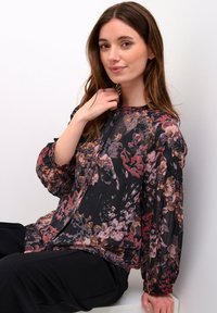 Schwarze Bluse mit Blumenmuster, die eine Mischung aus roten und rosafarbenen Blumen zeigt, aus weichem Stoff mit langen Puffärmeln und einem runden Ausschnitt mit Knöpfen.