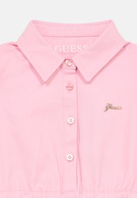 Ροζ ανοιχτόχρωμο πουκάμισο με γιακά, κατασκευασμένο από βαμβάκι, με μπροστινό κλείσιμο με πλαστικά κουμπιά και μικρό χρυσό λογότυπο στο στήθος.