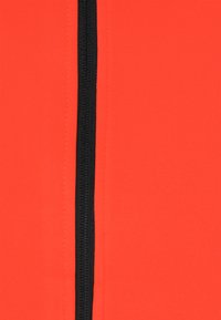 Roter dehnbarem Stoff mit glatter Textur, ausgestattet mit einem zentralen schwarzen Reißverschluss. Das Material wirkt leicht und figurbetont.