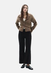Brown wool blend cardigan with a collared design, featuring a button closure. Paired with high-waisted black wide-leg trousers and black shoes.