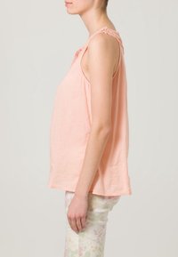 Peach-colored sleeveless top with lace trim at shoulders, loose fit, made from lightweight fabric, featuring a soft texture and round hem.
