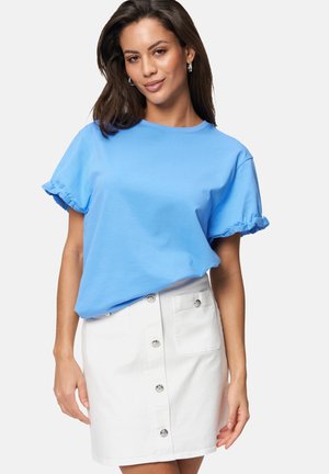 Light blue short-sleeve t-shirt with ruffled cuffs paired with a white denim skirt featuring front buttons and two side pockets.