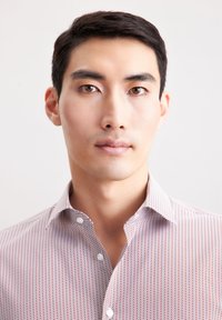 Camicia bianca e rossa con un colletto botton-down, caratterizzata da un design geometrico e una leggera trama, indossata da un uomo.