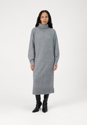 Gray knit sweater dress with a high collar, long sleeves, a knee-length hem, and ribbed accents at the cuffs and bottom. Worn with black boots.