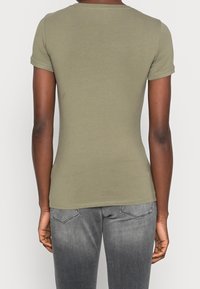 Olive green cotton short-sleeve t-shirt with a crew neck, fitted shape, and a plain texture. Back view shows stitching detail and smooth finish.
