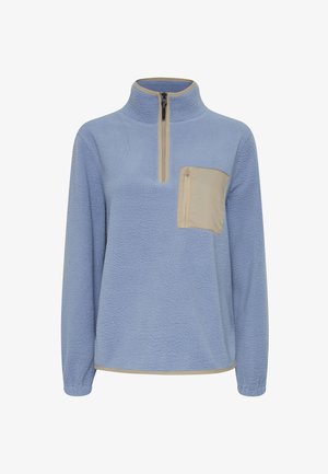 Kék polár pulóver fél cipzárral, bézs mellzsebből, hosszú ujjakkal és struktúrált felülettel. Az alsó részén kontrasztos díszítéssel rendelkezik.