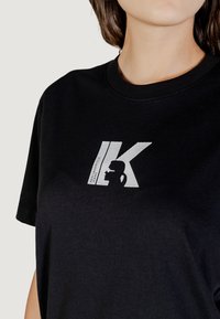 Camiseta de algodón negra con un logo gráfico en blanco que contrasta. Cuello redondo y mangas cortas, con una textura suave.