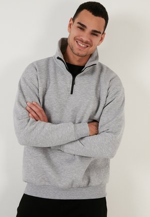 Grey half-zip sweatshirt with a textured finish, ribbed cuffs, and hem. Features a black zipper and a high collar design.