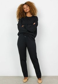 Black, lightweight cotton sweatsuit with a relaxed fit. Long sleeves, drawstring waist, and minimalist design with no patterns. Simple, smooth texture.