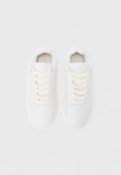 Λευκά αθλητικά παπούτσια με λείο δερμάτινο επάνω μέρος, κρέμ κορδόνια, στρογγυλερή μύτη, οπές για αερισμό και μαλακό επενδεδυμένο κολάρο.