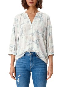 Blouse légère à motif bleu pâle et crème, dotée d'un col en V, de manches 3/4 et d'une coupe décontractée, portée avec un jean en denim bleu.