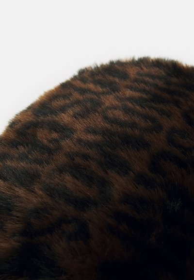Brūnas un melnas leopardu raksta audums ar mīkstu, teksturētu virsmu, parādot izteiktu traipu rakstu uz noapaļotas formas.