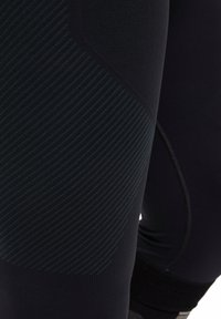Leggings de sport noirs avec un tissu texturé à rayures horizontales, une coupe près du corps et une conception de taille sans couture.