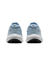 Zapatillas deportivas de color azul claro con parte superior de tela, contornos suaves, suela de goma y un logo negro de Nike en la parte posterior. Textura del talón redondeada visible.