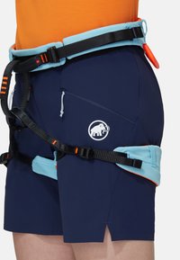 Blå klättringsshorts med svarta remmar, en orange detalj och en vit logotyp. Inkluderar en sidoficka med dragkedja och en kontrasterande midja.