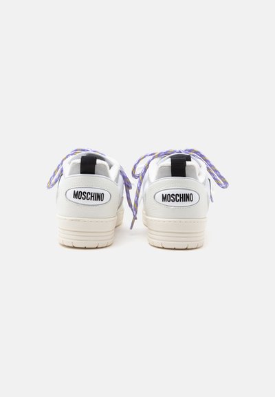 Λευκά sneakers Moschino με μωβ και κίτρινα κορδόνια, εμφανίζεται από πίσω σε απλό ανοιχτό φόντο.