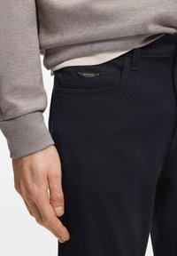 Σκούρο μπλε παντελόνι ναυτικού χρώματος με λεία υφή, διαθέτει ένα μικρό ασημένιο λογότυπο στην μπροστινή τσέπη και στενή εφαρμογή.