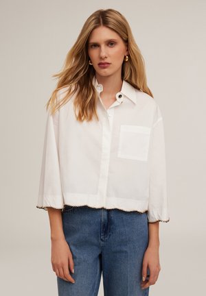 Weißes, kurzes Shirt aus leichtem Stoff, mit Punktkragen, Knopfverschluss, Brusttasche und gewelltem Saum mit Perlenakzenten.