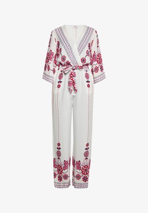 Combinaison blanche avec broderies florales rouges et bleues, décolleté en V, manches trois-quarts, taille cintrée avec ceinture assortie, silhouette à jambes larges.