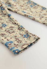 Katoenen ribstof in lichtgroen, met een bloemenpatroon in blauw en bruin. Close-up van de vouw en textuur van de stof.