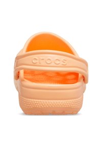 Des Crocs de couleur pêche avec un design à bout fermé, une sangle arrière réglable, une surface texturée et une semelle texturée pour une meilleure adhérence.