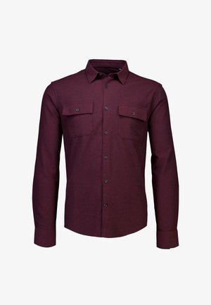 Burgundin pitkähihaista nappipaitaa, joka on valmistettu teksturoituneesta kankaasta. Paidassa on kaksi rintataskua läpillä ja mustilla napeilla.