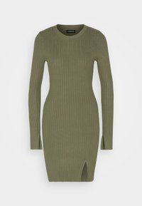 Robe à manches longues côtelée de couleur vert olive, avec un col rond et des fentes latérales, confectionnée dans un tissu extensible pour une silhouette ajustée.