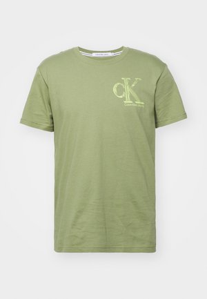 Oliwkowa bawełniana koszulka z krótkim rękawem, okrągłym dekoltem i jasnżółtym logo Calvin Klein Jeans na lewej piersi.