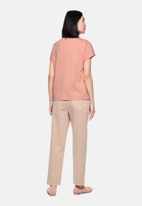 Light pink short-sleeve top, paired with beige wide-leg pants. The pants feature back pockets and a relaxed fit. Simple, clean design.