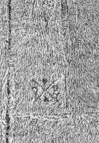 Gray fuzzy fleece garment with a high collar, featuring a central zipper and an embroidered logo at the bottom left. Soft, textured appearance.