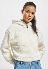 Kremfarget fleece-hettegenser med halv glidelås, strukturert stoff, elastisk nederkant og kengurulomme, kombinert med høytlivs denim.