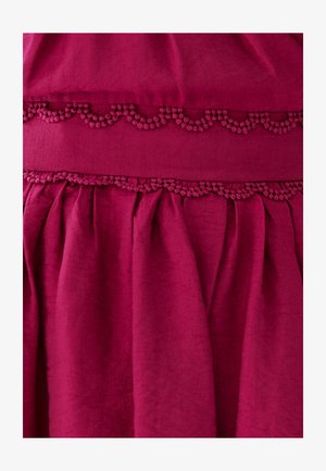 Fuchsia stoffen kledingstuk met een textuur, gegolfde rand en plooien. Zachte, gladde textuur met een rijke, levendige kleur.