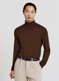 Brauner Rollkragenpullover aus weichem Strickmaterial, mit langen Ärmeln und taillierter Passform, getragen mit beigen Hosen und einem schwarzen Gürtel.