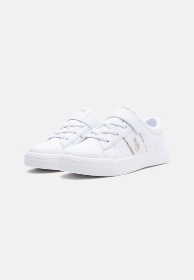 Par de zapatillas blancas de perfil bajo con cordones y una cinta de velcro, con un pequeño logo bordado en el lateral.