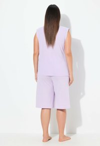 Lila kurzärmeliges Pyjama-Oberteil kombiniert mit passenden knielangen Shorts, die ein dezentes Muster aufweisen. weicher, leichter Stoff mit lockerer Passform.