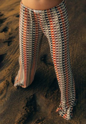 Weit geschnittene Hosen aus leichtem Stoff mit einem Muster aus ineinandergreifenden Kreisen in Rot, Marineblau und Weiß, mit weicher Textur.